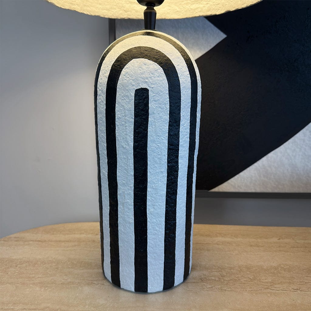 Table lamp with black and white striped design on a wooden surface.