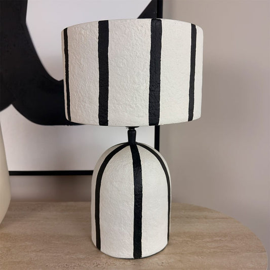 Table lamp with black and white striped design on a wooden surface.