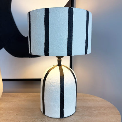 Table lamp with black and white striped shade on a wooden surface