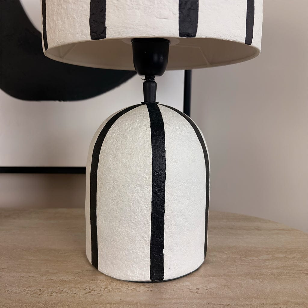 Table lamp with a black and white striped design on a wooden surface.