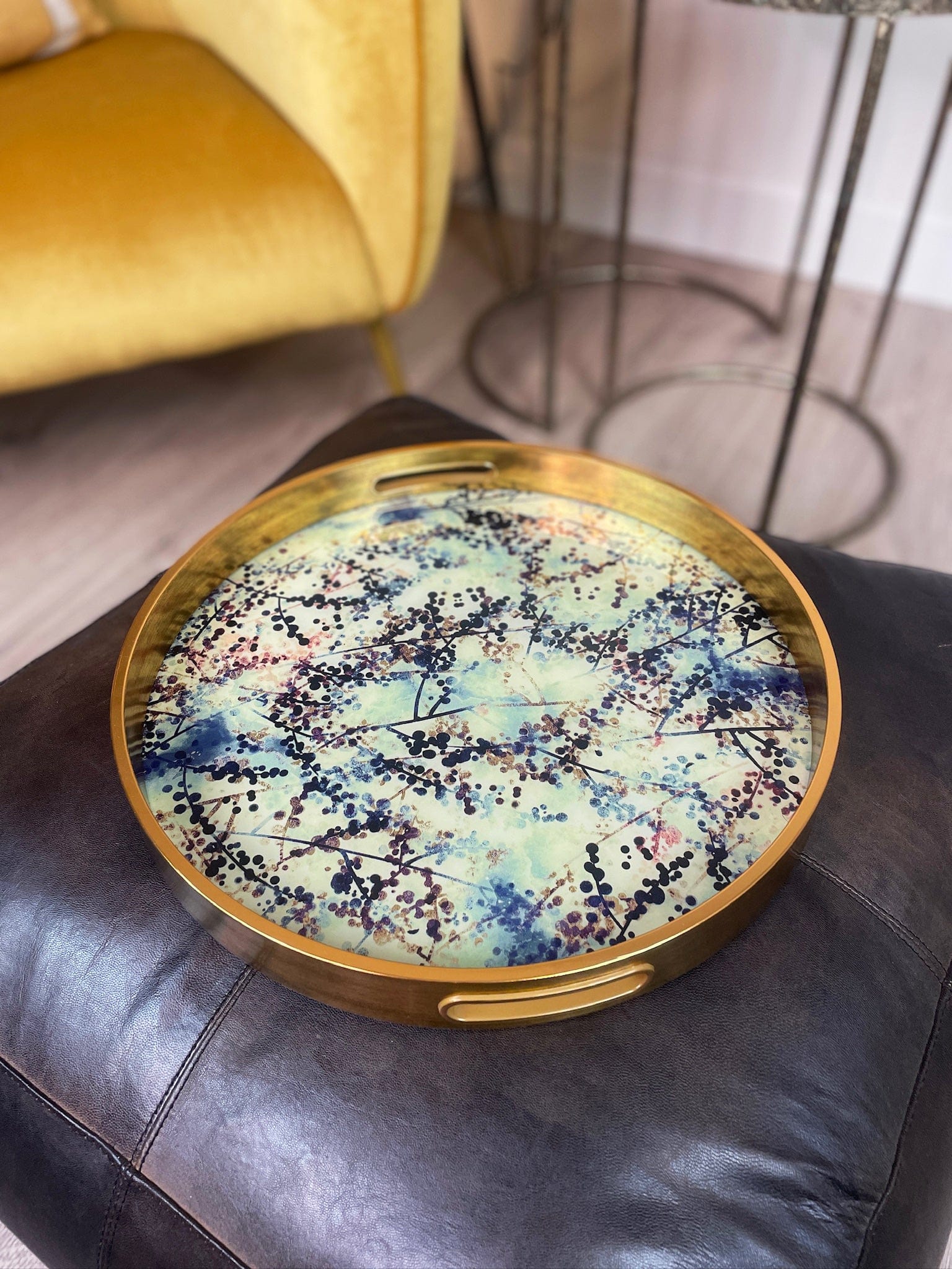 Decorative round tray with artistic design on a leather surface