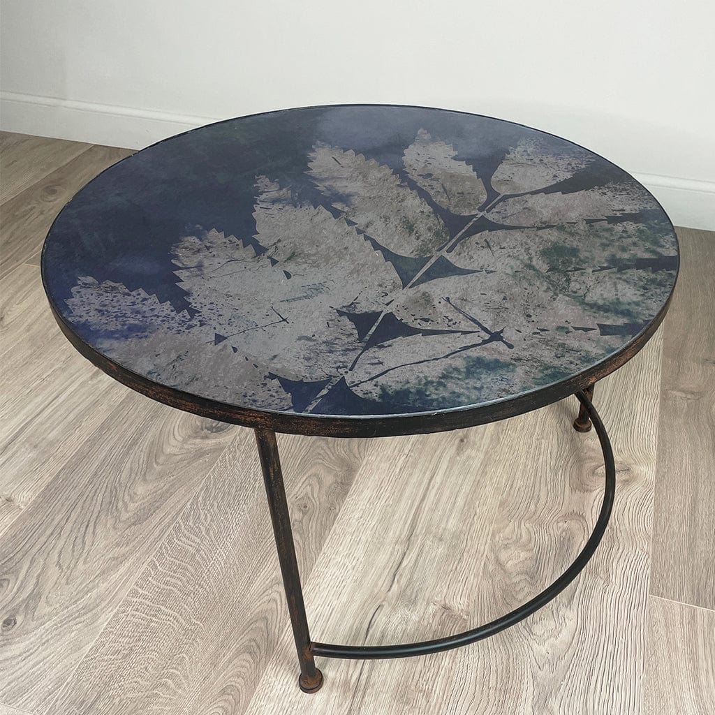 Round table with leaf-patterned top on a wooden floor