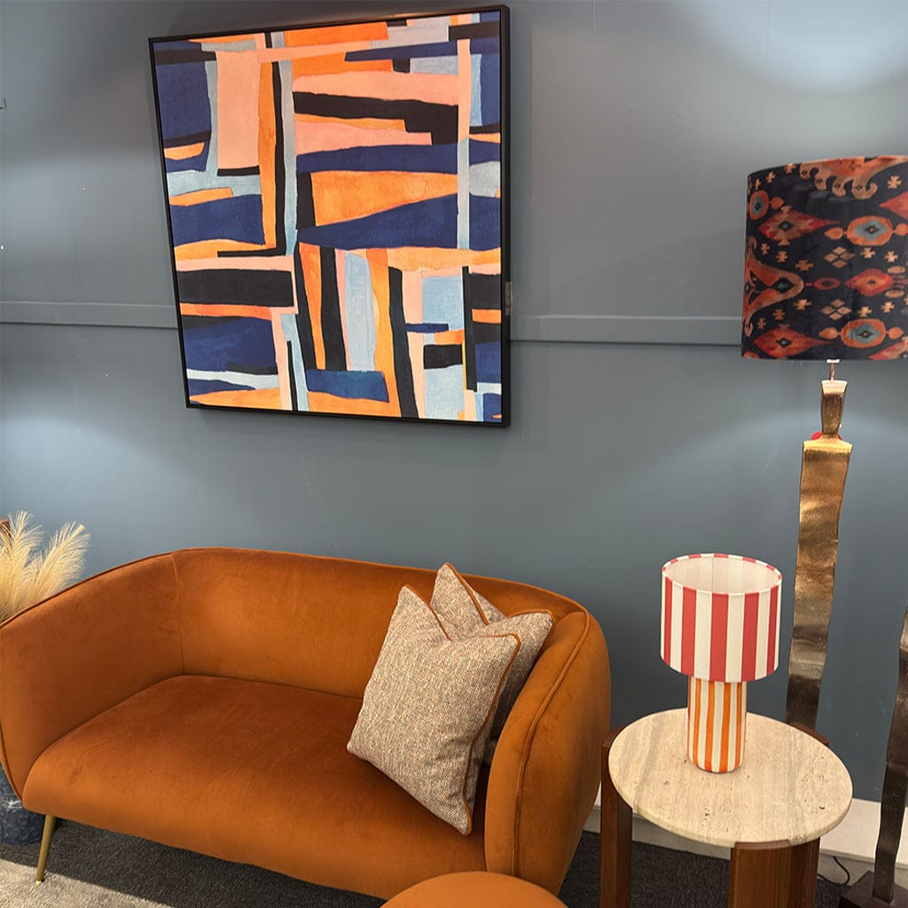 Living room with orange sofa, abstract art, and colorful lamp.