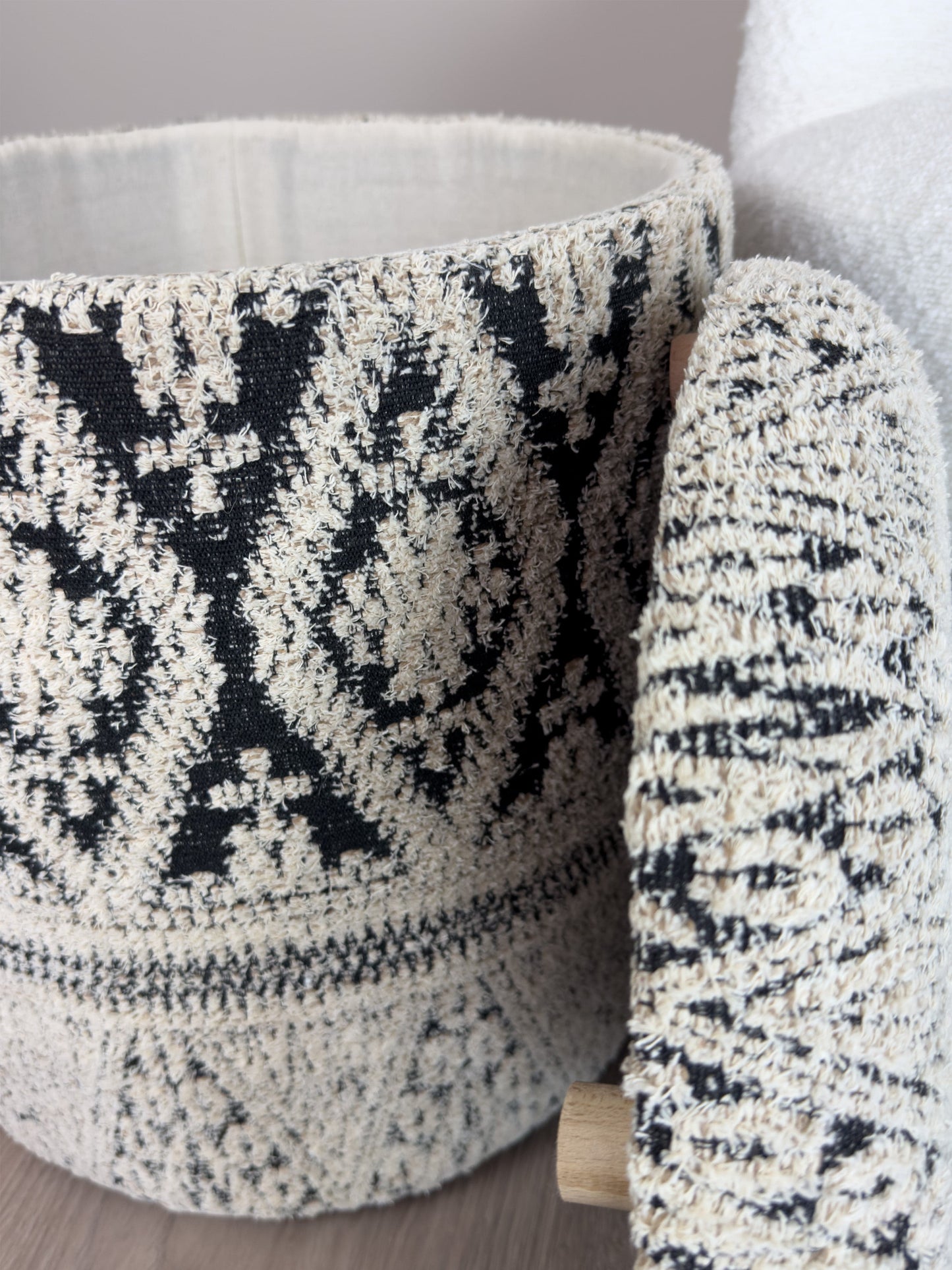 Textured black and white patterned ottoman against a neutral background