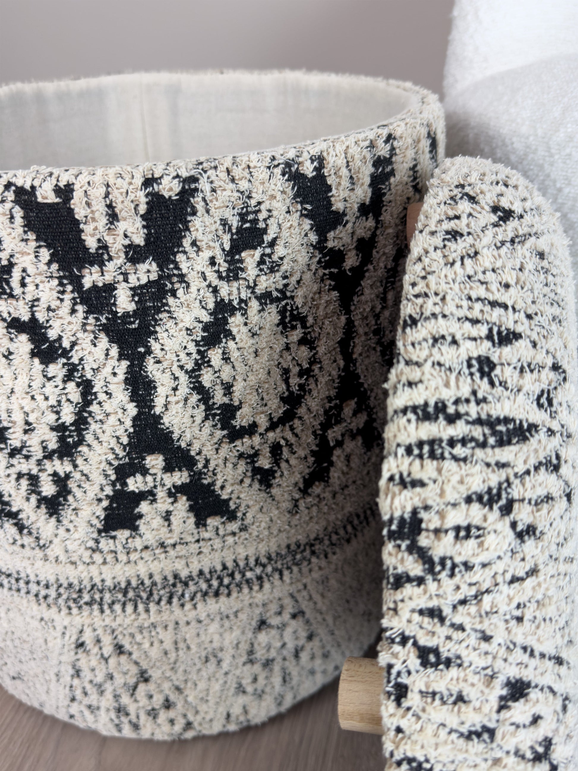 Textured black and white patterned ottoman against a neutral background