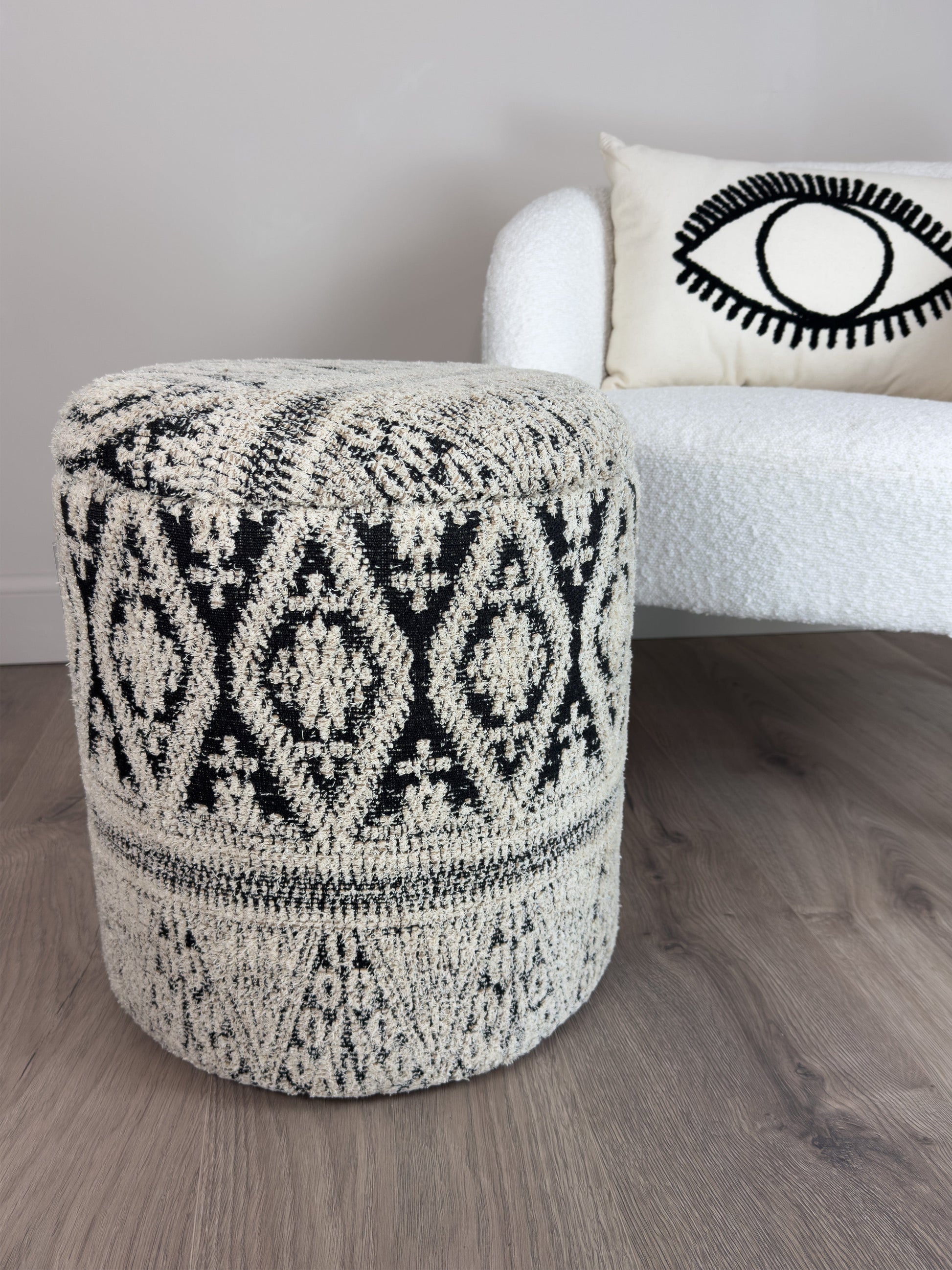 Patterned ottoman in front of a white sofa with a decorative pillow.