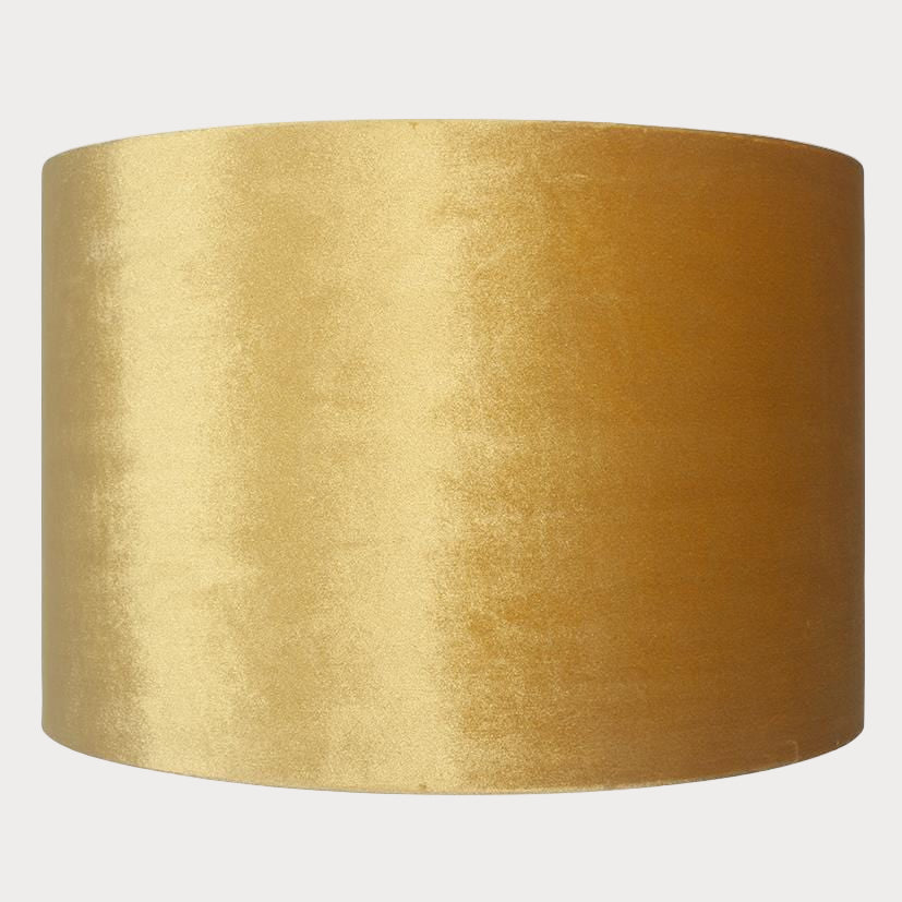 A cylindrical velvet lampshade in mustard color with a bronze lining, displayed against a plain background.
