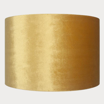 A cylindrical velvet lampshade in mustard color with a bronze lining, displayed against a plain background.