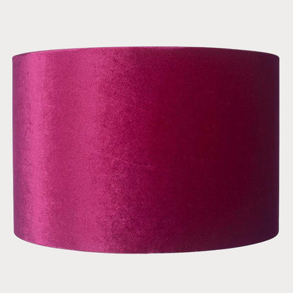 A cylindrical velvet lampshade in raspberry pink color with a bronze lining, displayed against a plain background.