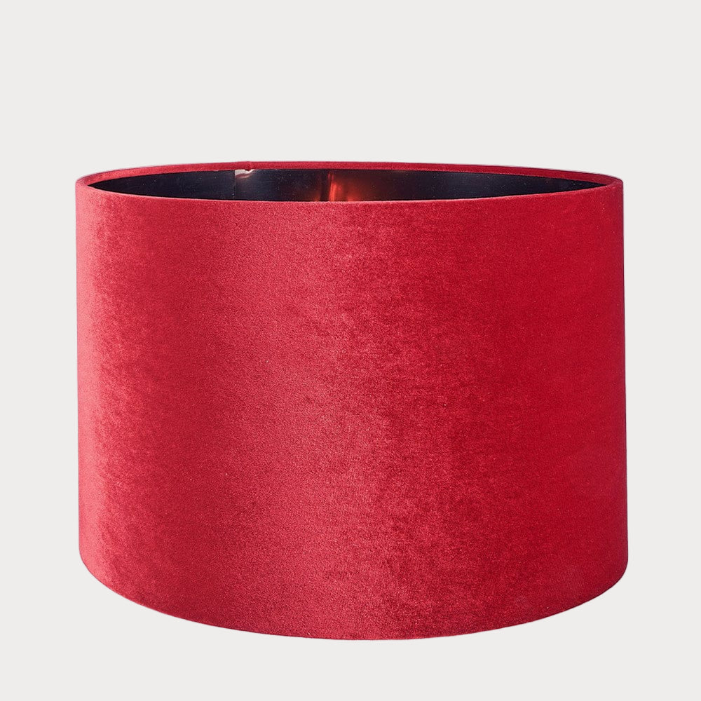 A cylindrical velvet lampshade in red color with a bronze lining, displayed against a plain background.
