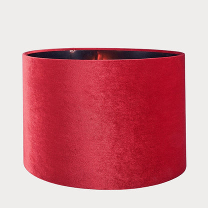 A cylindrical velvet lampshade in red color with a bronze lining, displayed against a plain background.