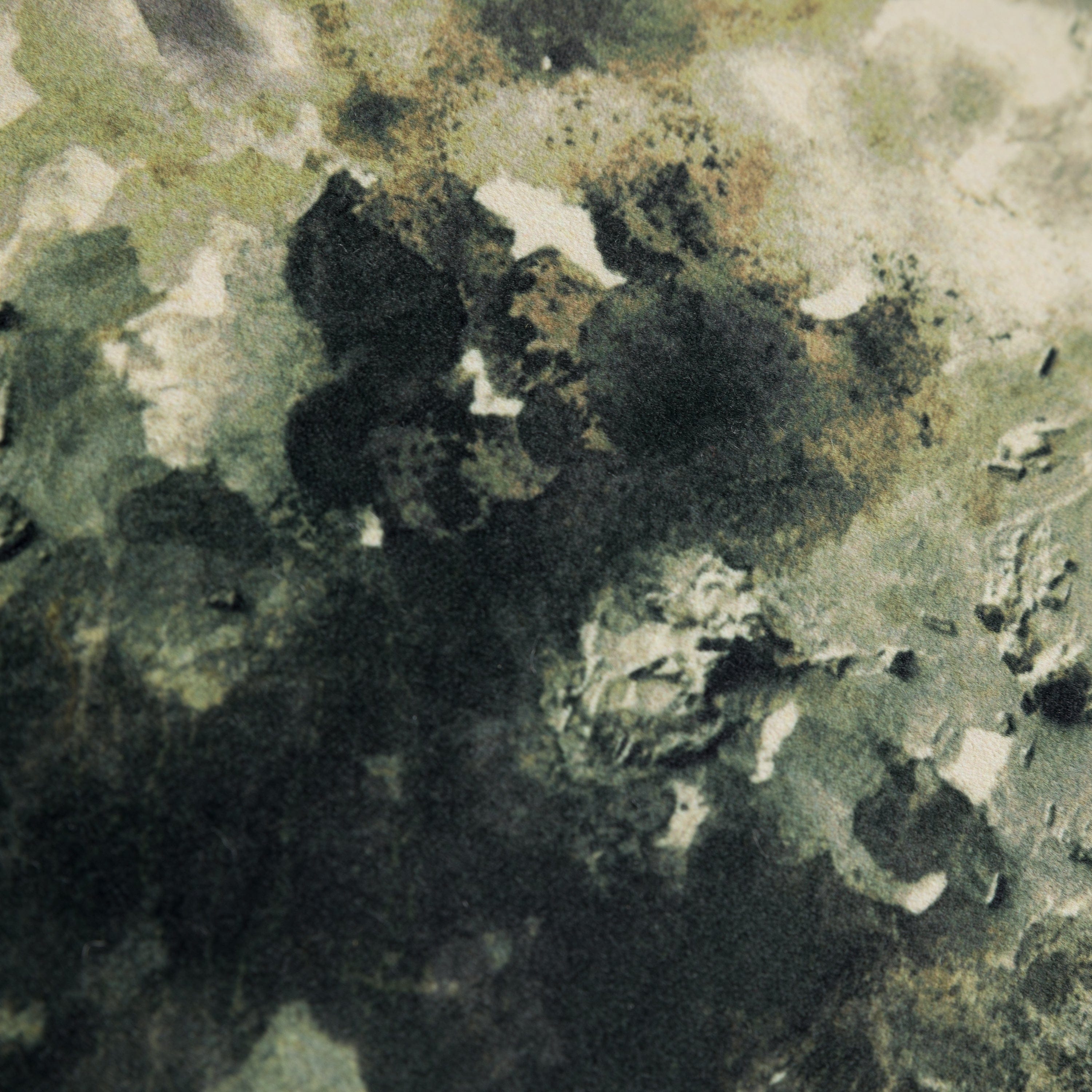 Close-up of a textured green velvet cushion surface with black and white patterns