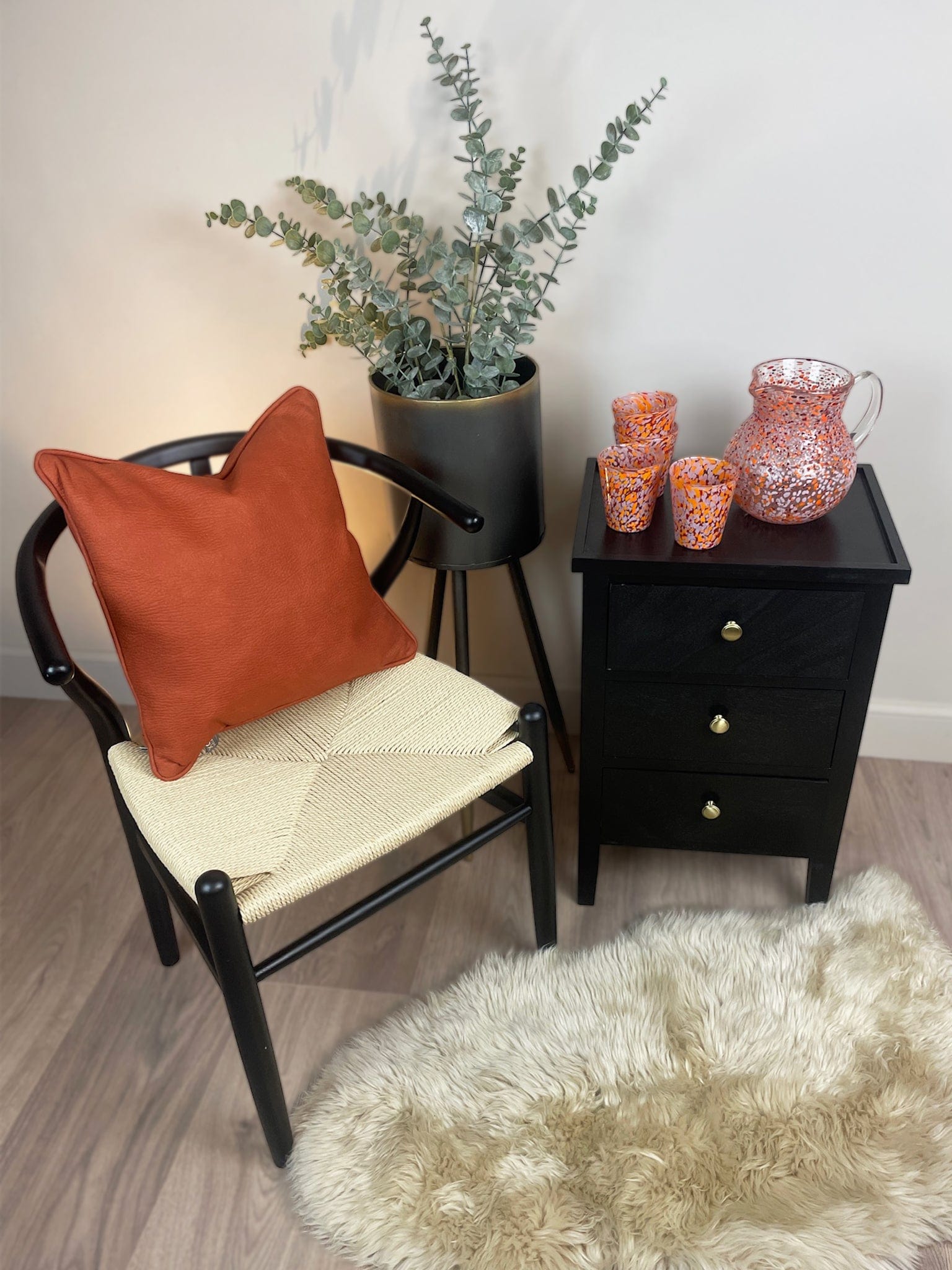 Chair with an orange cushion and a small table with decorative items in a room.