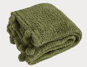 Folded green blanket with pom-pom details on a white background