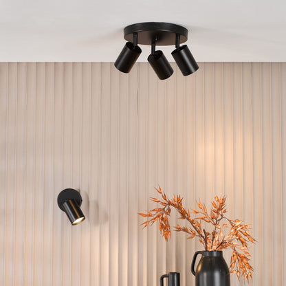 Modern ceiling light fixture on a neutral wall with decorative vases and branches.