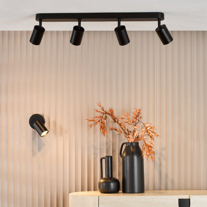 Modern interior design with black ceiling lights, vases, and a console table against a striped wall.