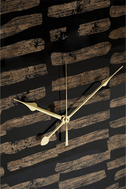 Gold clock on a textured black and brown wall