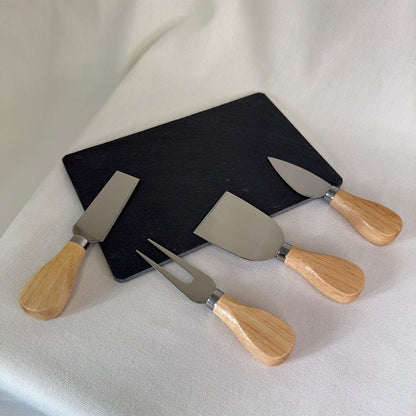 Set of four cheese knives with wooden handles on a black board against a white background