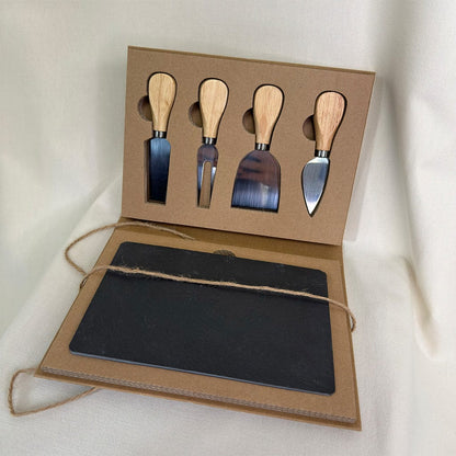 Set of four metal cheese knives with wooden handles in a cardboard box on a white background