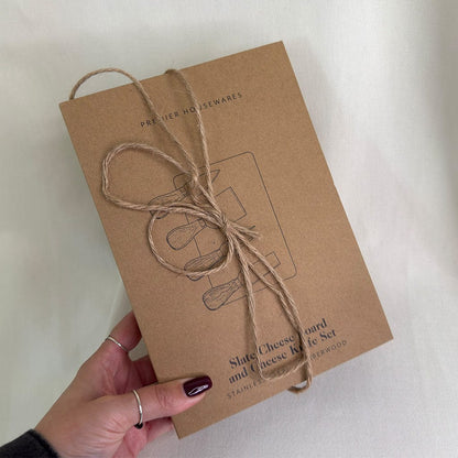 Kraft paper box with twine bow held by a hand on a light background