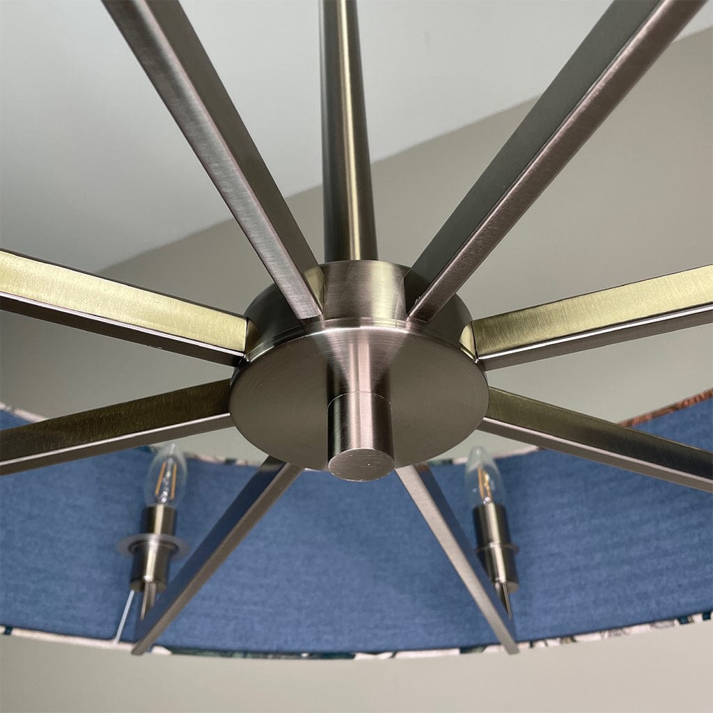 Close-up of a ceiling chandelier with metallic blades against a blue and white striped background.