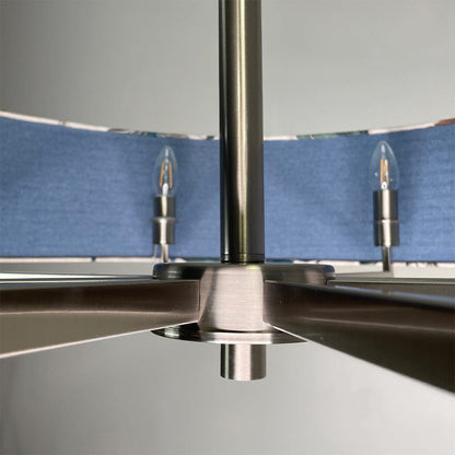 Close-up of a metallic ceiling fan with blue blades against a gray background