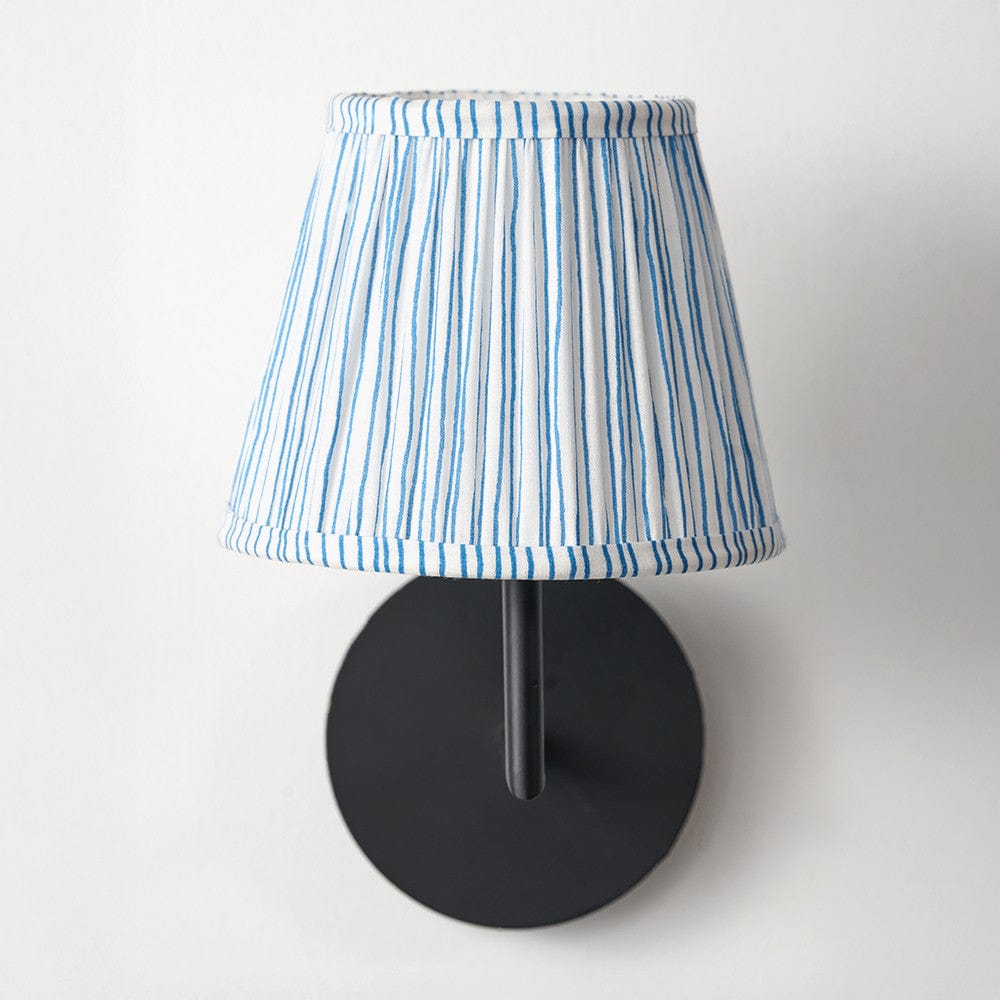 Wall-mounted lamp with a blue and white striped shade on a white background