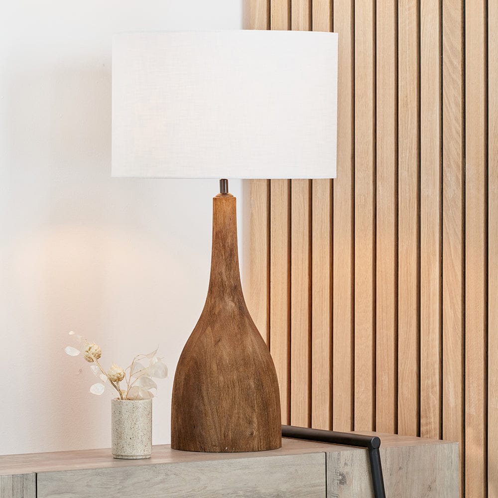 Wooden table lamp with a white shade on a wooden surface.