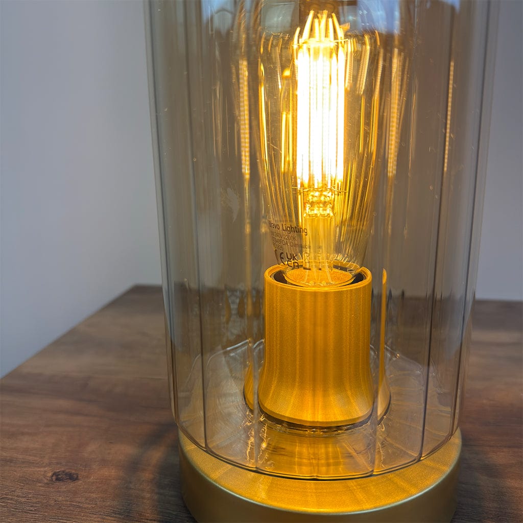 Light bulb inside a ribbed amber glass lamp on a wooden surface