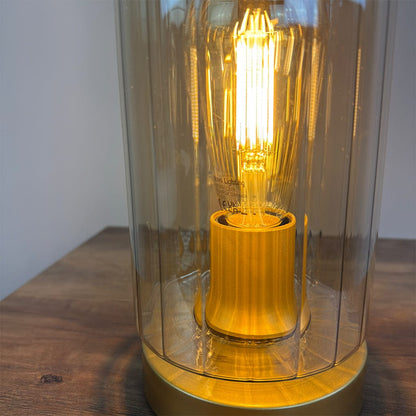 Light bulb inside a ribbed amber glass lamp on a wooden surface