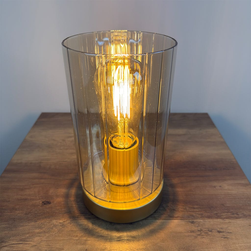 Table lamp with a amber glass shade and visible bulb on a wooden surface.