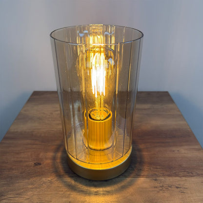 Table lamp with a amber glass shade and visible bulb on a wooden surface.