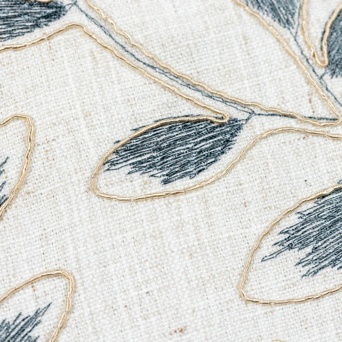 Close-up of embroidered fabric with blue leaves on a beige background