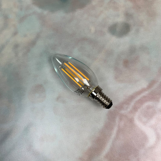 An E14 clear candle non-dimmable LED bulb with visible filaments inside, placed against a marble background.