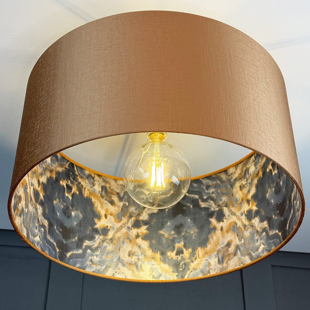 Lamp with a brown shade and marble pattern inside, featuring a lit bulb.