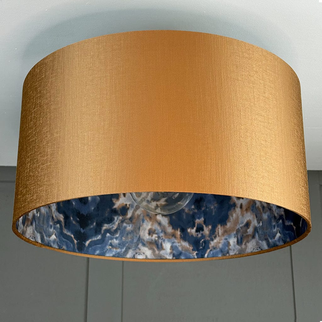 Gold lampshade with a blue marble interior on a gray background