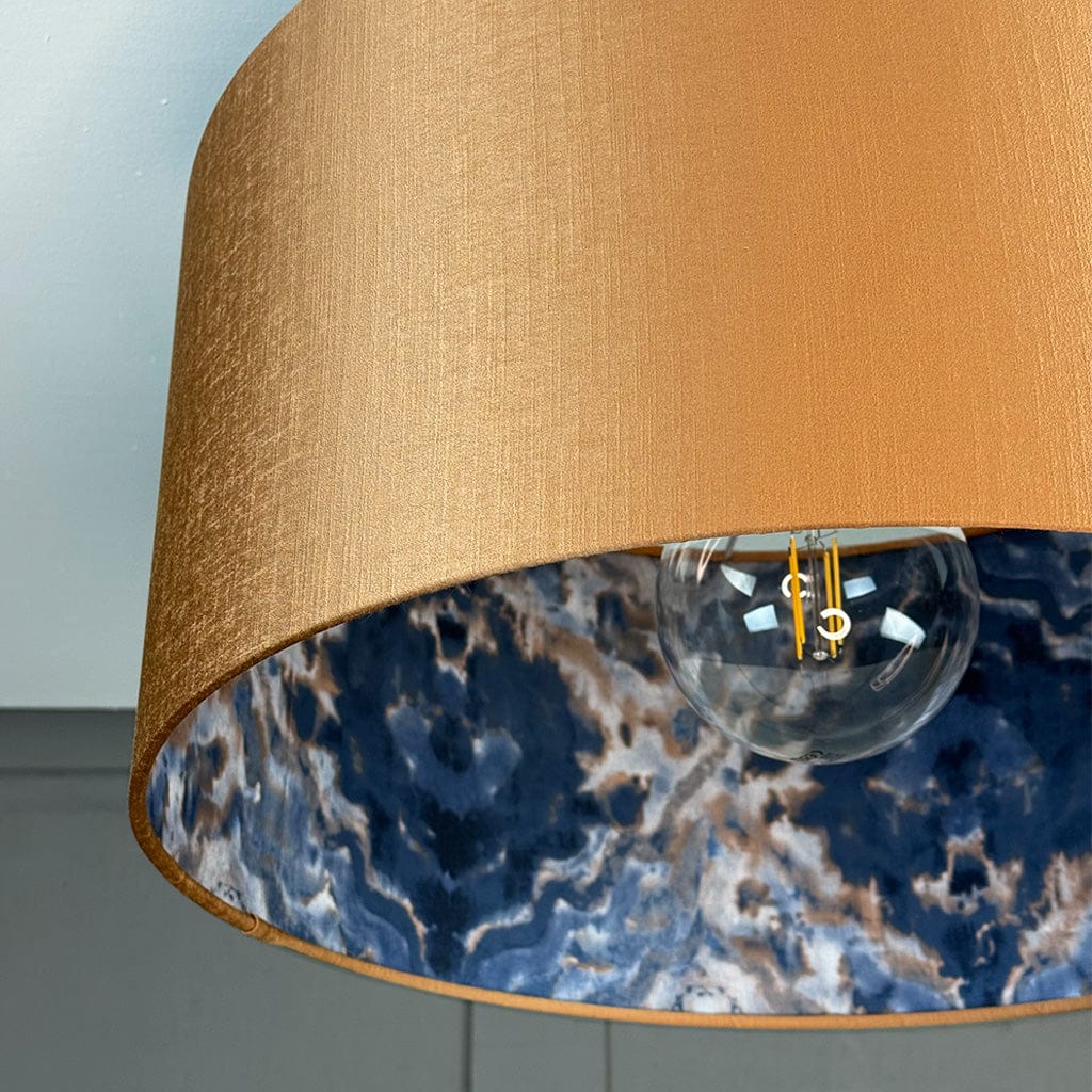 Close-up of a lamp with a brown shade and blue marble pattern inside.