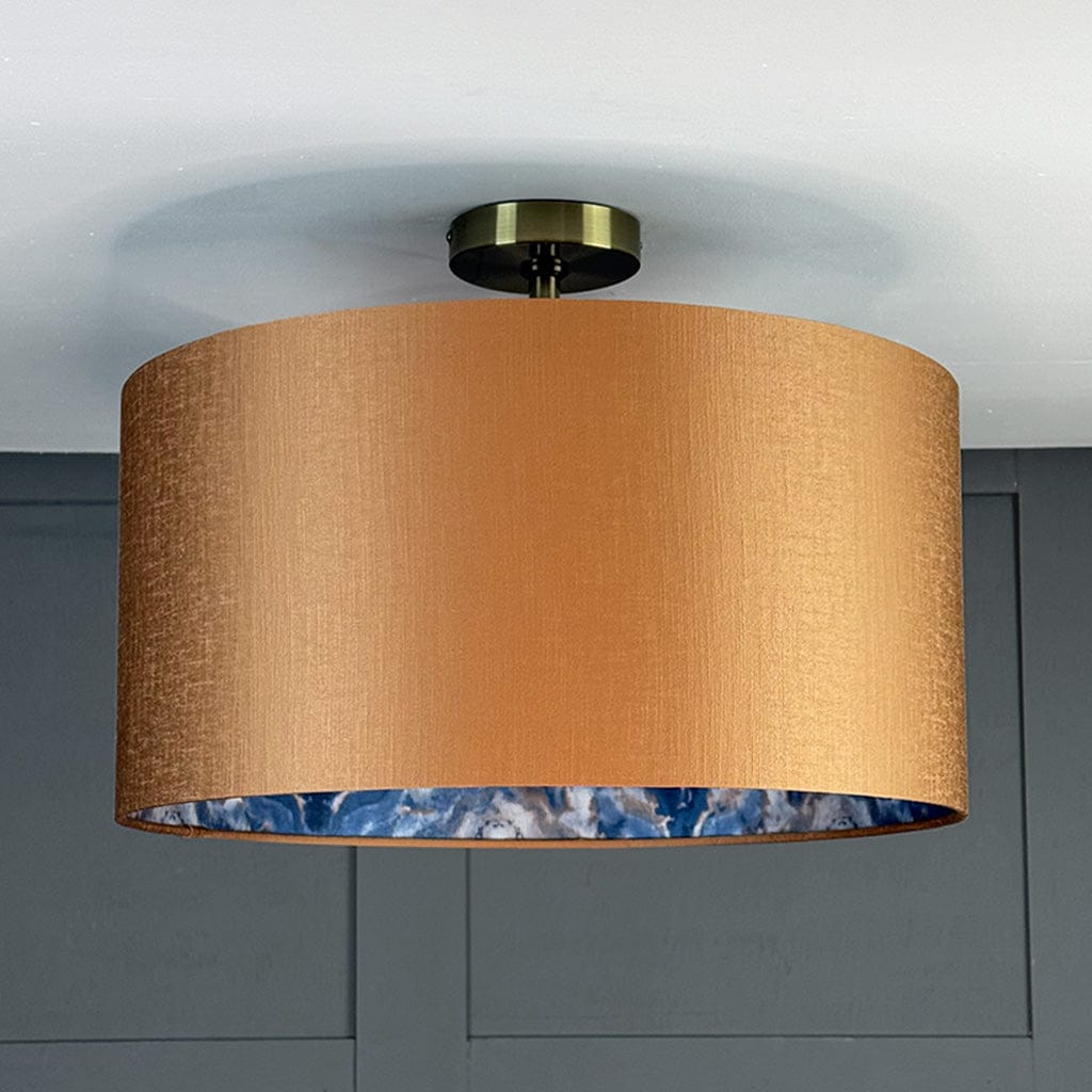 Ceiling light fixture with a gold shade and blue interior against a gray wall.