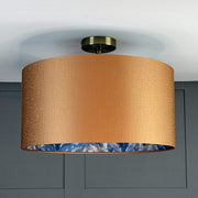 Ceiling light fixture with a gold shade and blue interior against a gray wall.