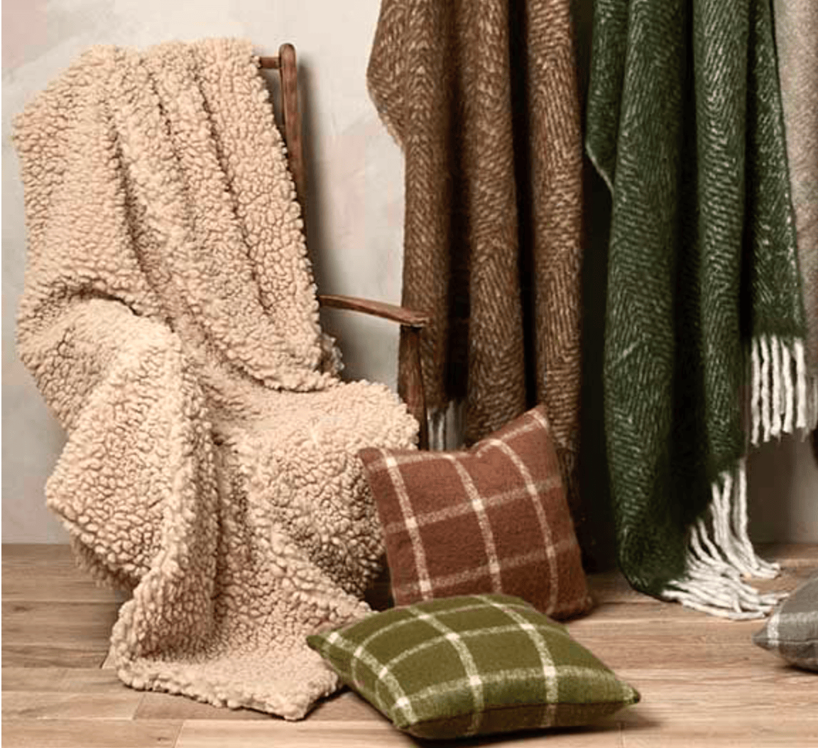 Collection of textured blankets and pillows on a wooden surface
