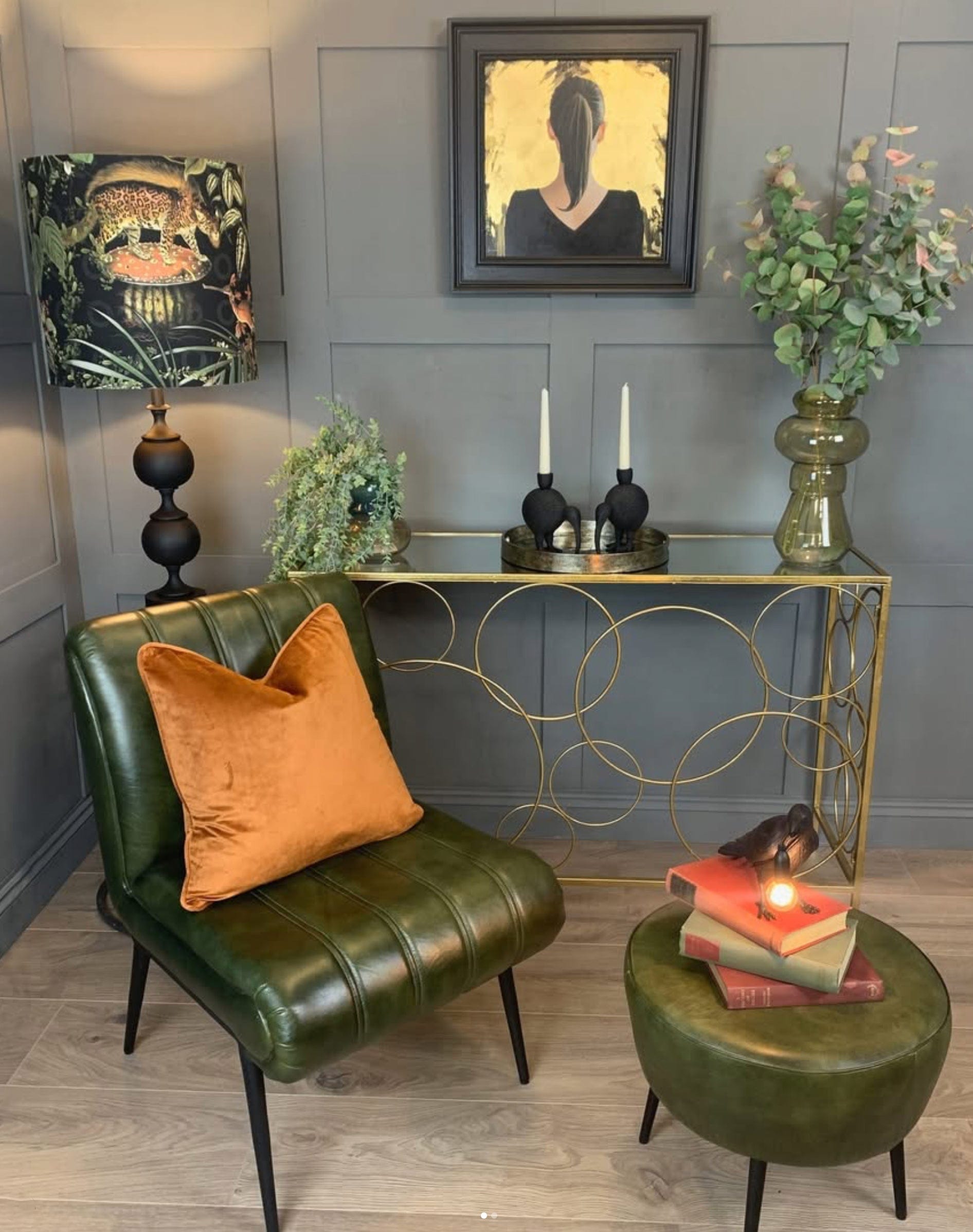 Green leather chair with an orange pillow in a room with decorative elements.