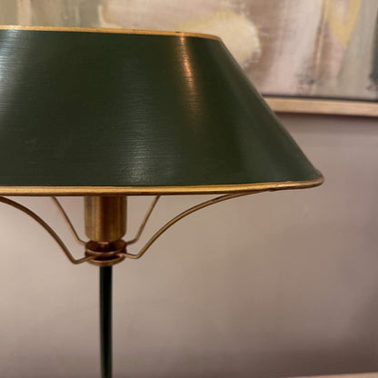 Floor lamp with a green shade and gold base against a neutral wall.