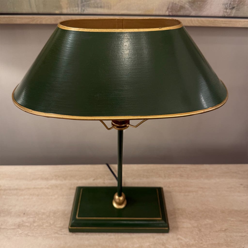 Green table lamp with a gold trim on a wooden surface.