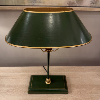 Green table lamp with a gold trim on a wooden surface.