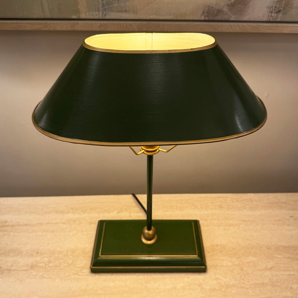 Vintage-style table lamp with a black shade and gold accents on a wooden surface.
