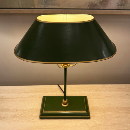 Vintage-style table lamp with a black shade and gold accents on a wooden surface.