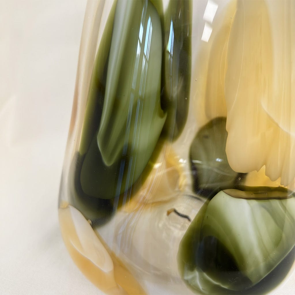 Close-up of a glass object with green and beige colors on a white background