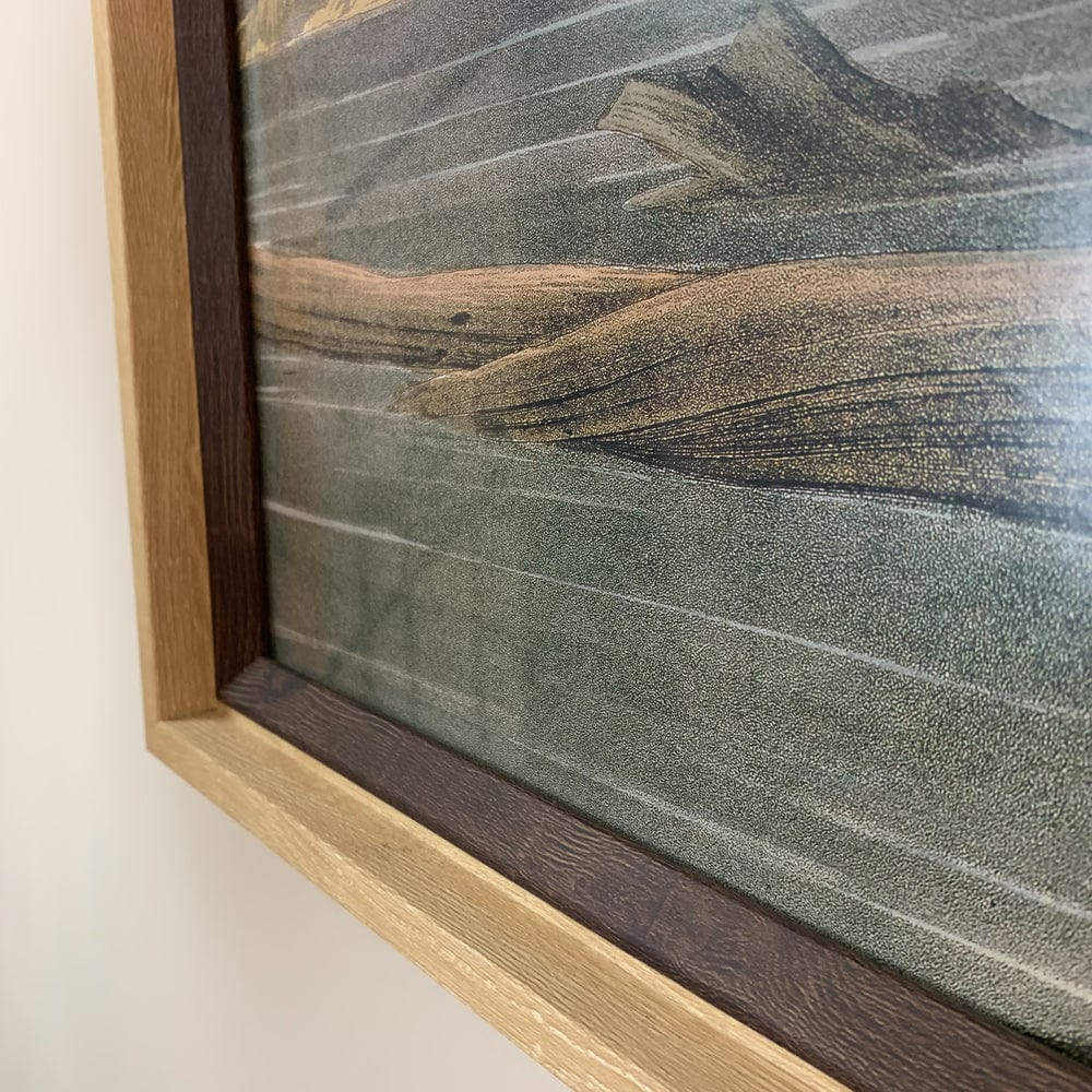 Framed artwork with a textured surface and wooden frame on a light background