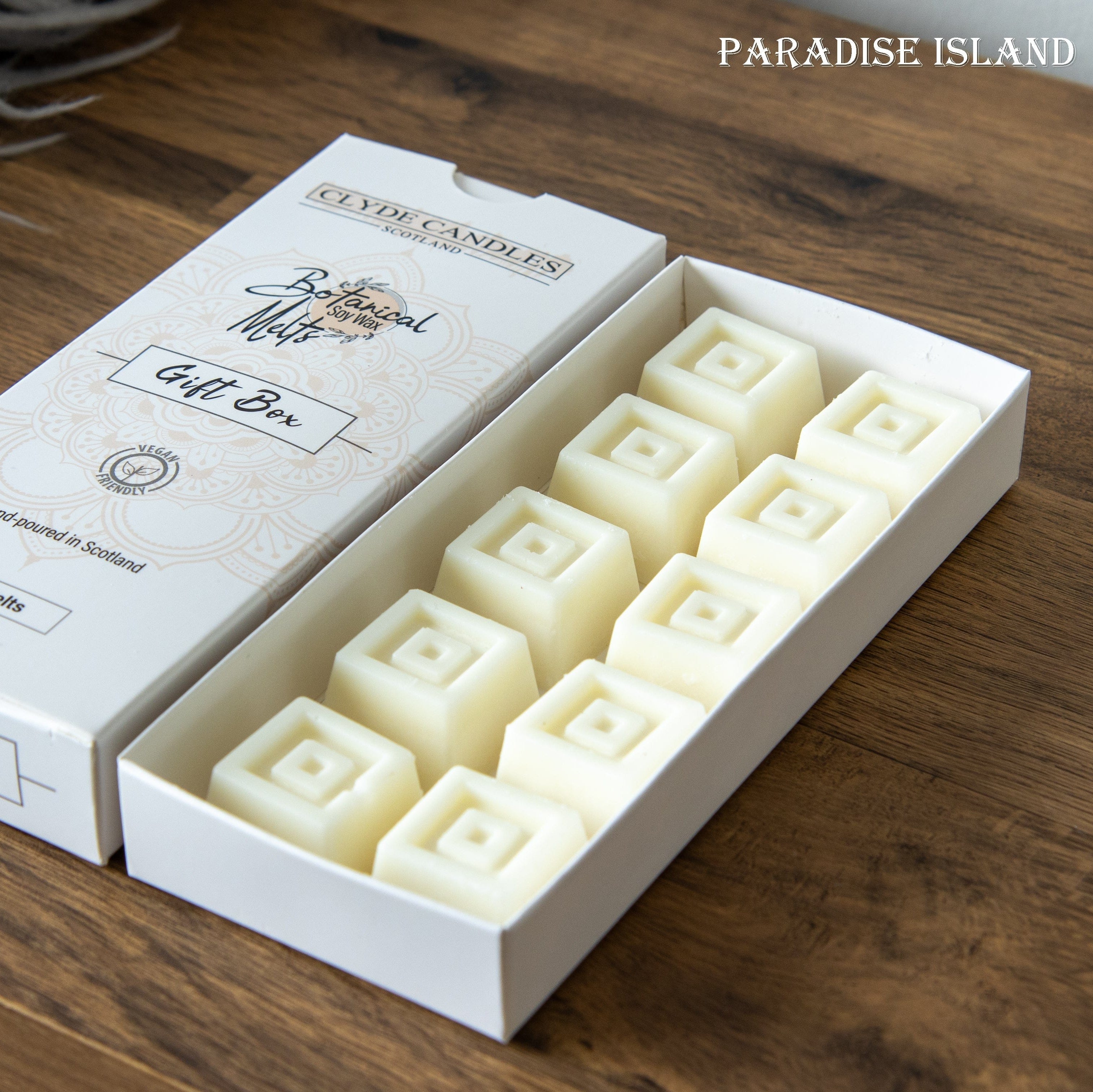 Box of Clive & Candace candles on a wooden surface with 'Paradise Island' branding.
