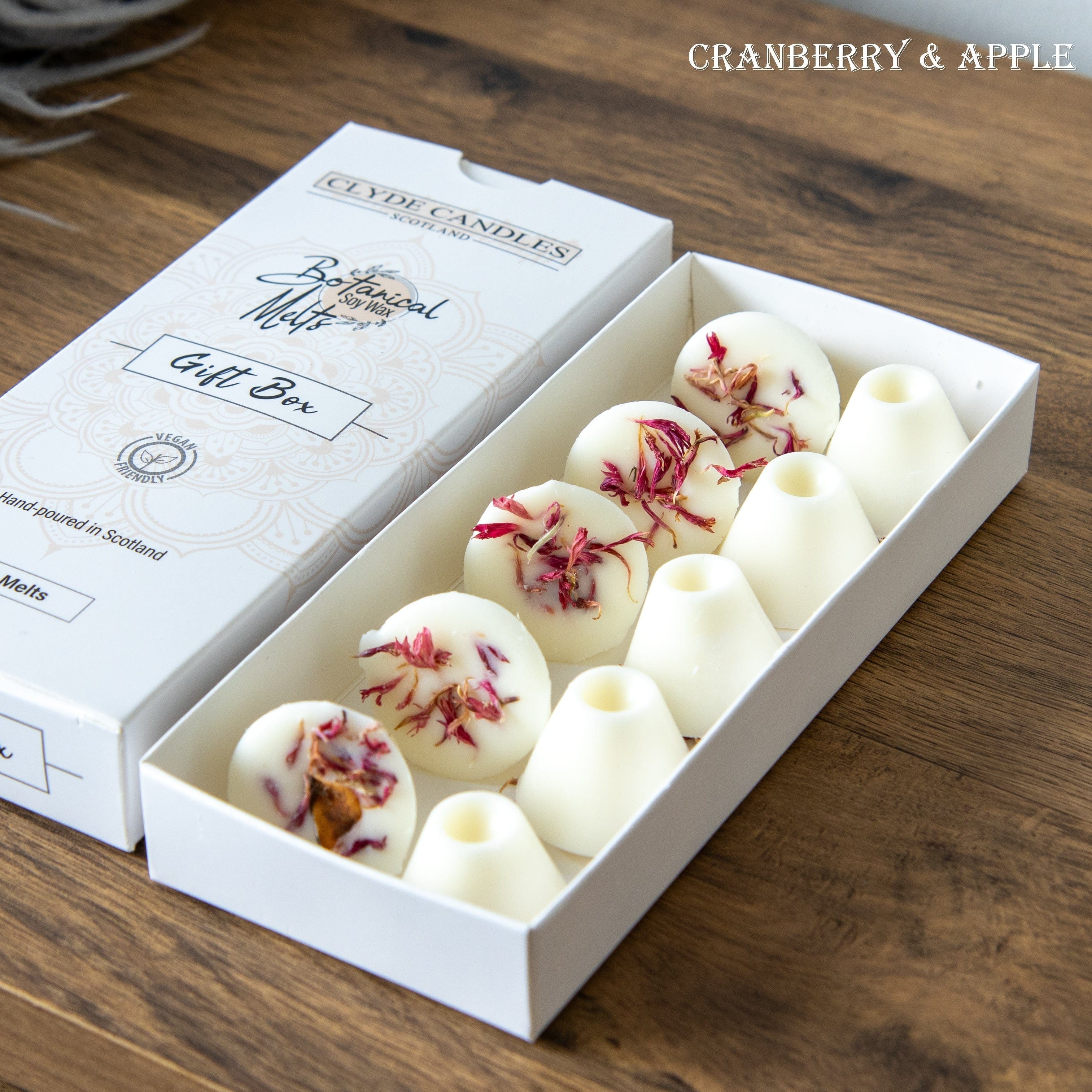 Candle gift box with white candles featuring cranberry and apple design on a wooden surface.